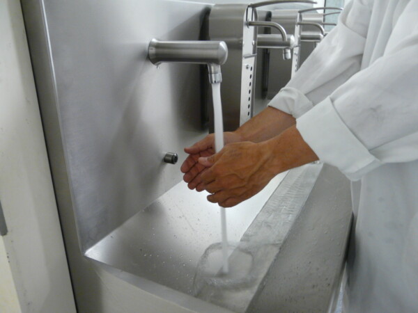 Handen wassen met sensor in een RVS handwasbak